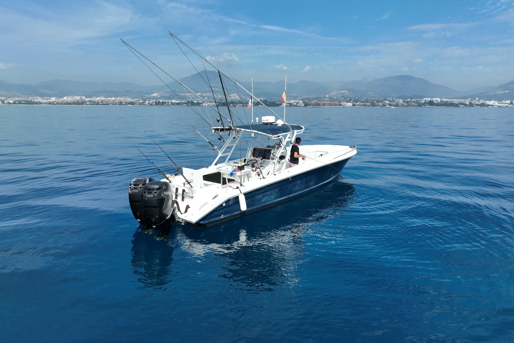 Drone view of the STRIKE 360 cockpit, with fishing rods ready and twin outboard engines at the stern