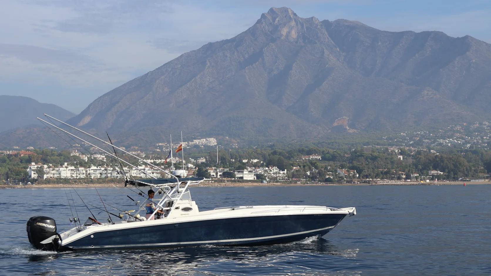 STRIKE 360 cruising off Marbella with its fishing rods rigged and La Concha mountain behind